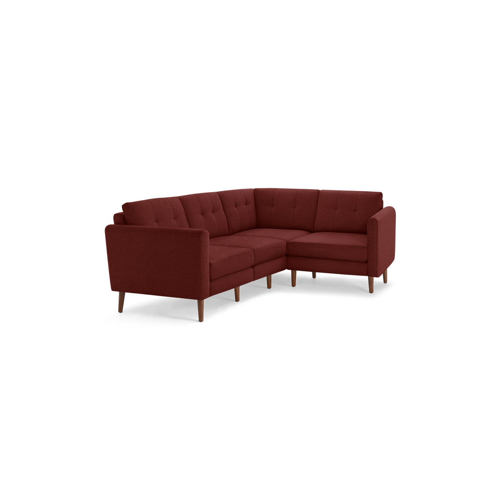 Modern L-shaped sectional sofa with tufted back cushions, upholstered in deep red fabric, supported by slender wooden legs.