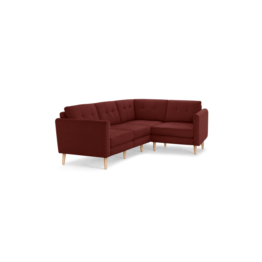 Modern L-shaped sectional sofa in deep red fabric with tufted back cushions and light wooden legs.