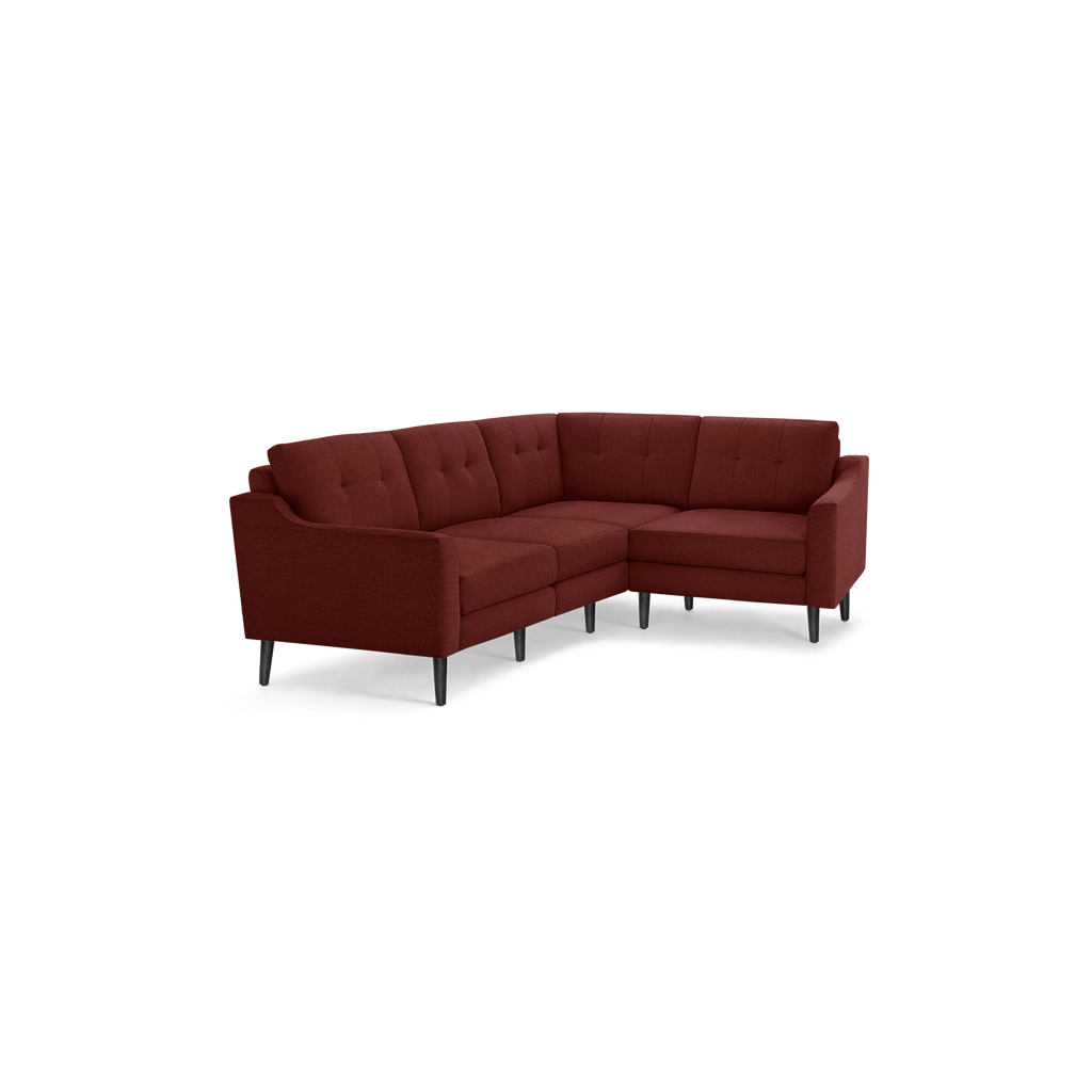 Mid-century modern L-shaped sectional sofa in rust red fabric with tufted back cushions and black tapered legs.