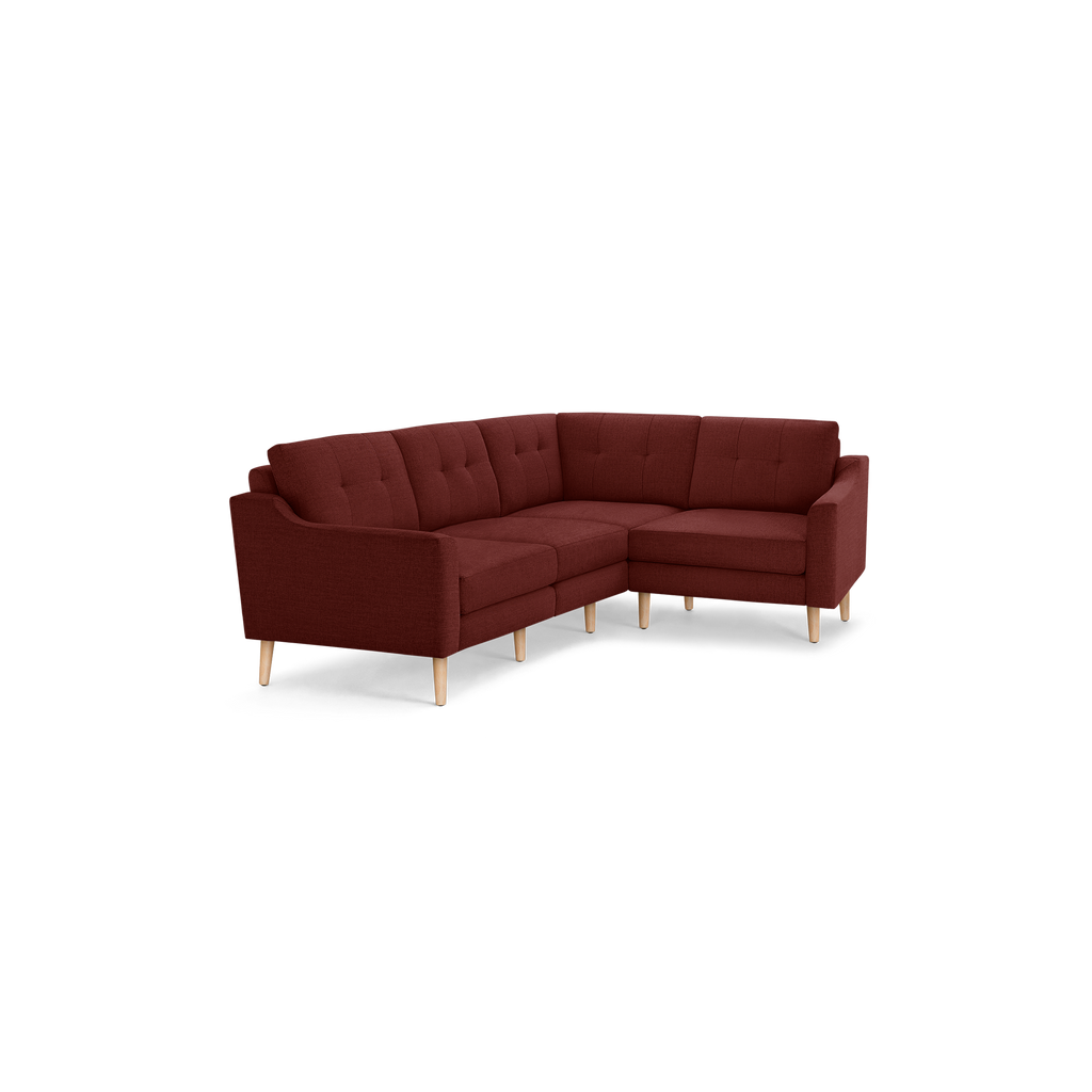 L-shaped sectional sofa with deep red fabric upholstery, tufted back cushions, and light wooden legs.