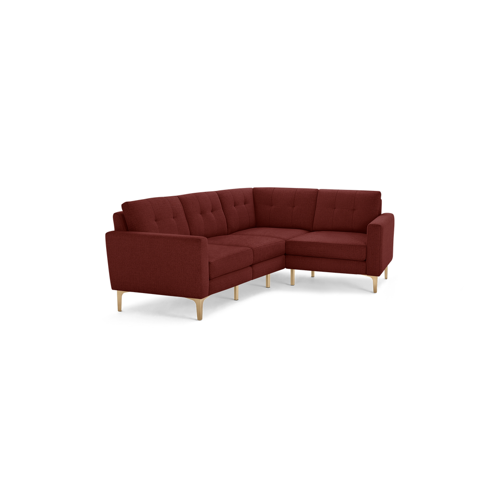 Modern L-shaped sectional sofa with tufted back cushions, deep red upholstery, and light wooden legs.