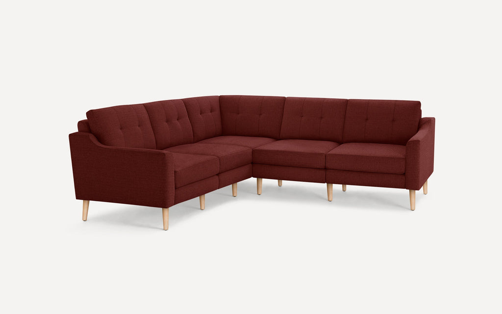 Mid-century modern L-shaped sectional sofa with tufted cushions, upholstered in deep red fabric and supported by light wooden legs.