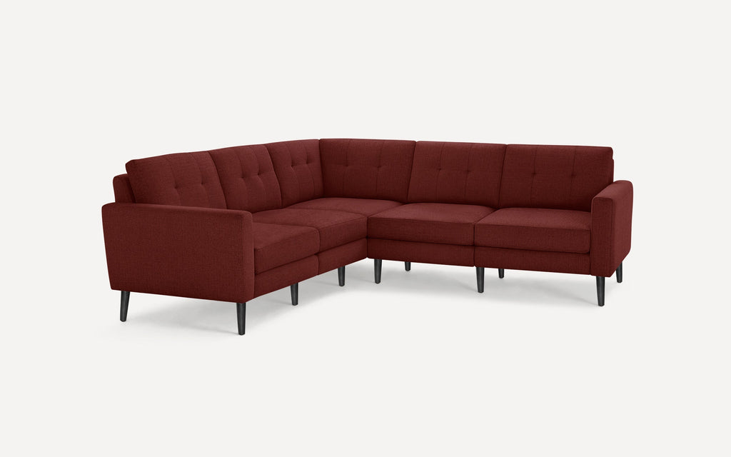 L-shaped modern sectional sofa in deep red fabric with tufted back cushions and slender black legs on white background.