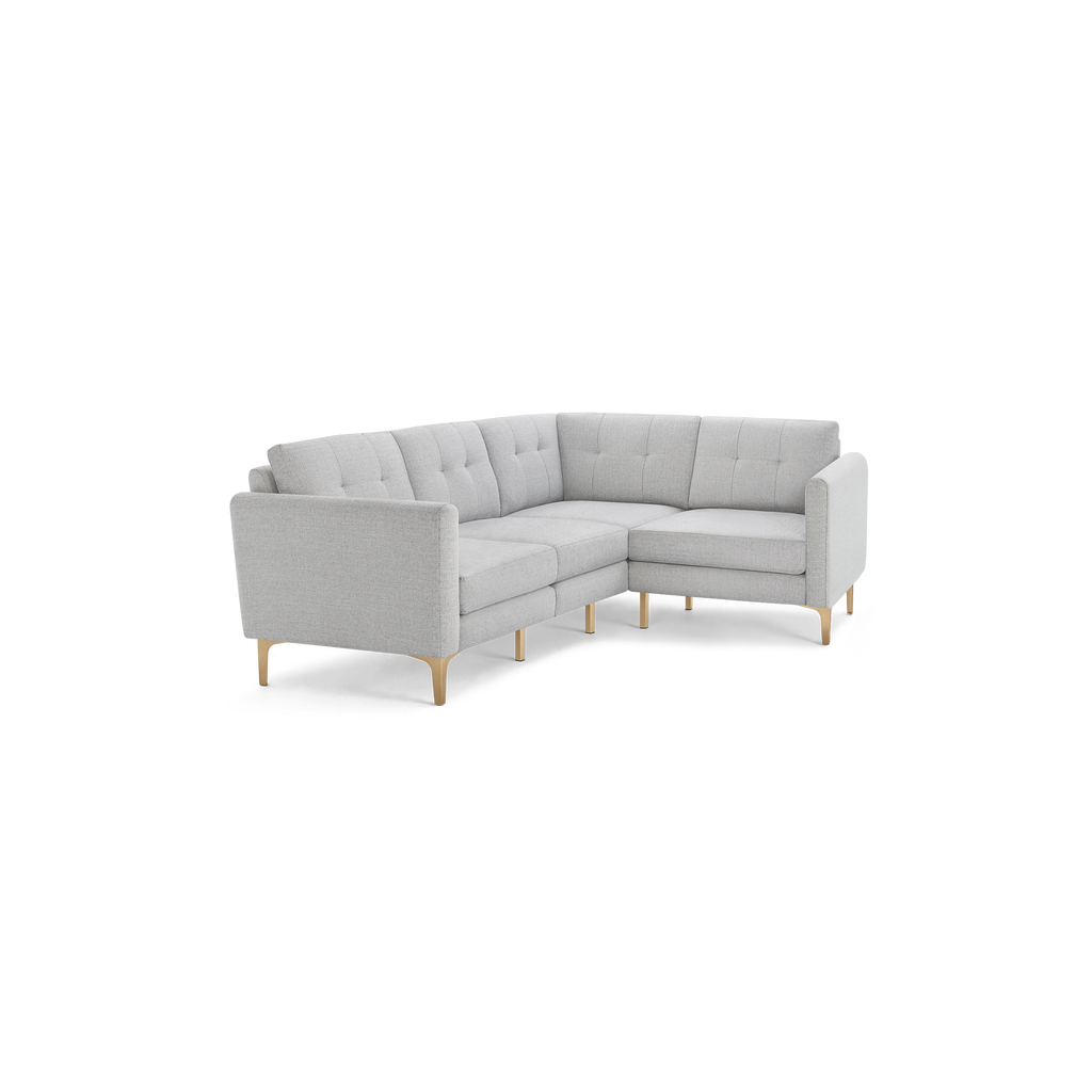 Light gray upholstered L-shaped sectional sofa with tufted back cushions and light wooden legs, modern minimalist design.