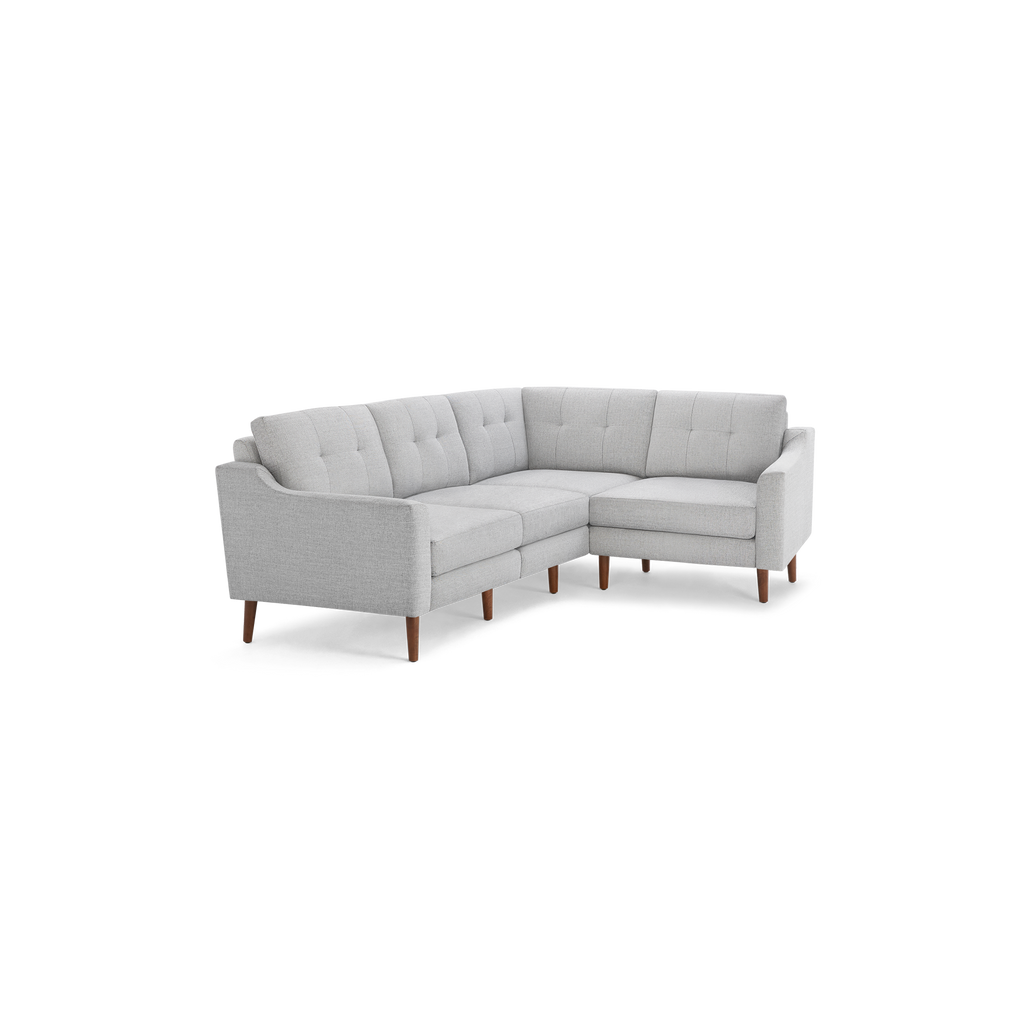 Light gray fabric sectional sofa with tufted back cushions, angled arms, and wooden tapered legs in a modern design.