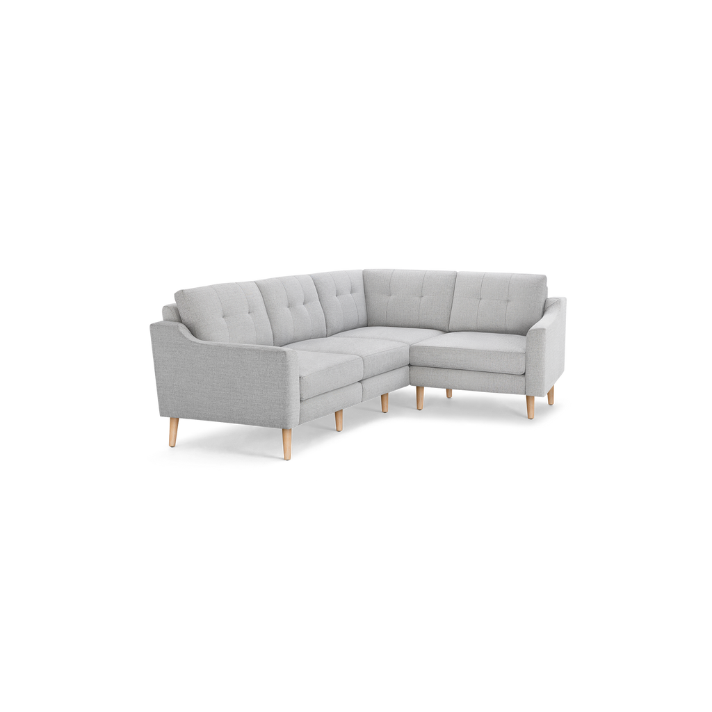 Light gray L-shaped sectional sofa with tufted back cushions and wooden legs, modern and minimalist design.