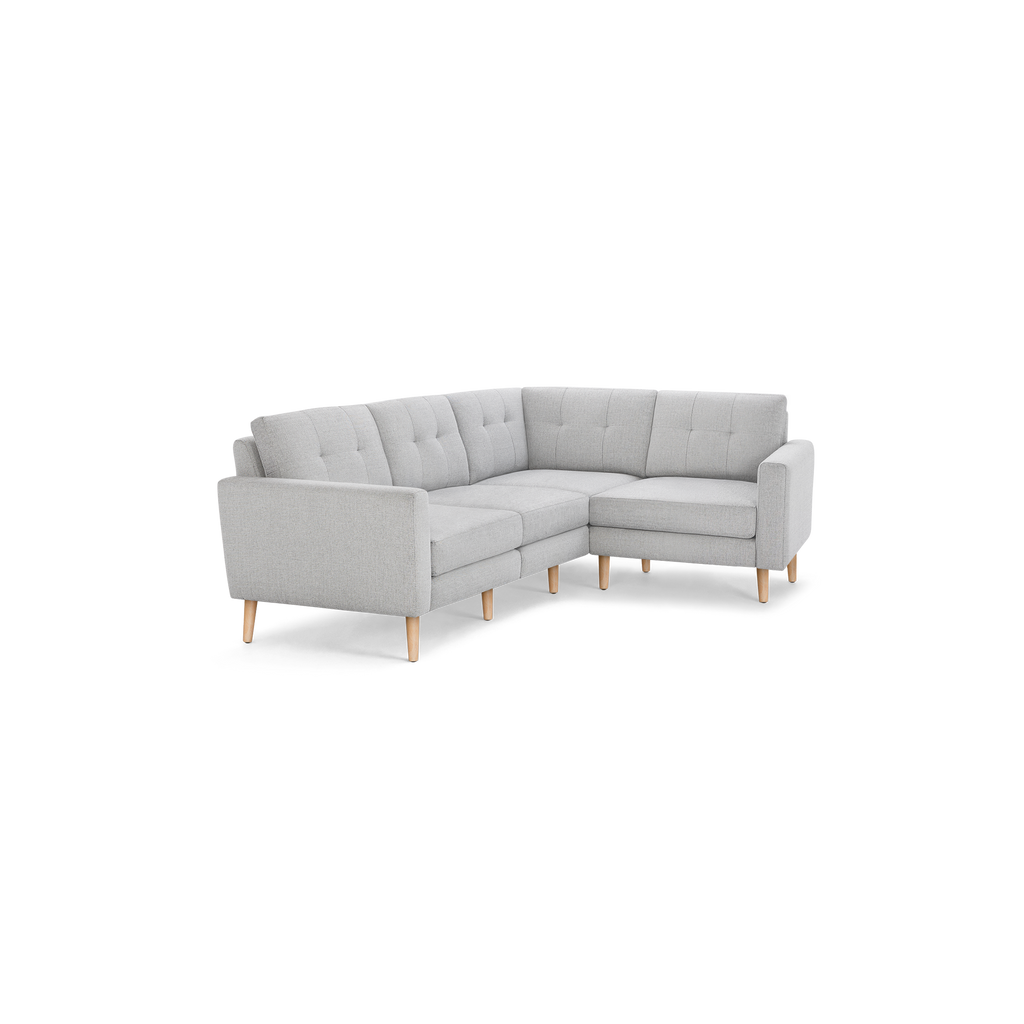 Light gray fabric L-shaped sectional sofa with tufted back cushions and wooden legs, modern minimalist design.