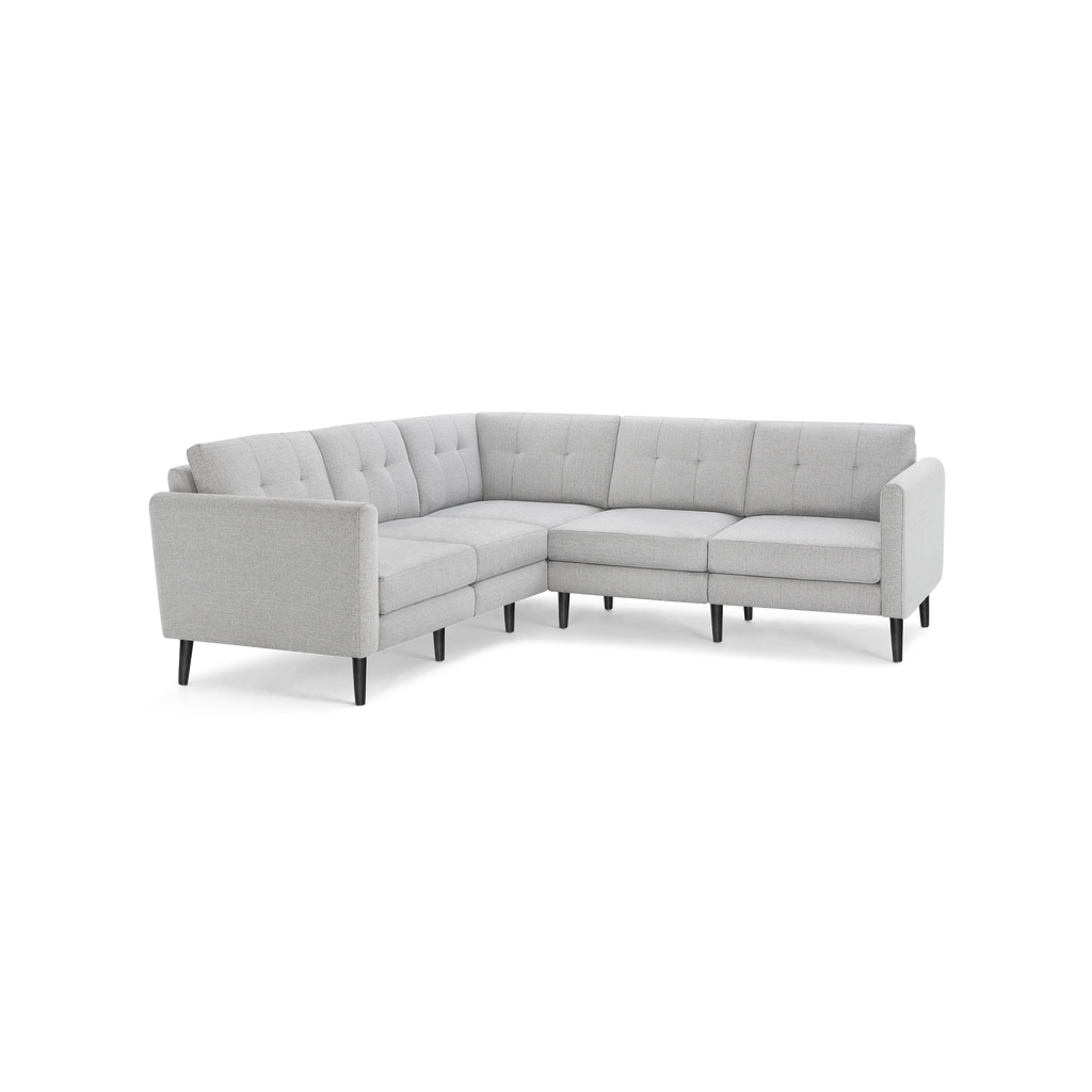 Light gray L-shaped sectional sofa with tufted cushions and black wooden legs on a black background.