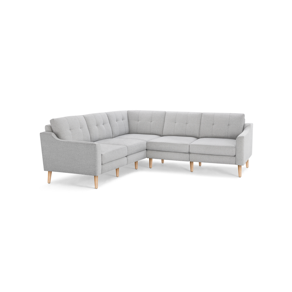 Light gray L-shaped sectional sofa with tufted back cushions and natural wood legs, modern and minimalist design.