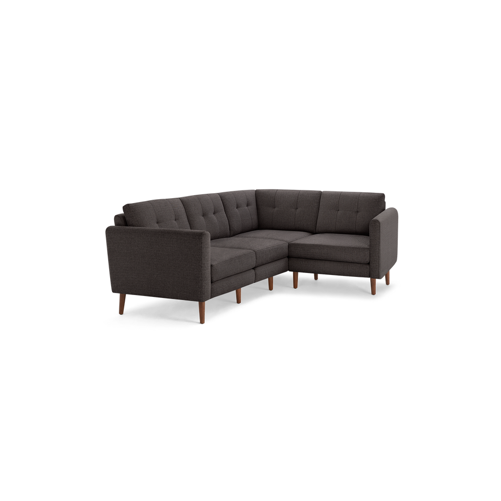 Dark gray L-shaped sectional sofa with tufted back cushions, wooden legs, and modern mid-century design.