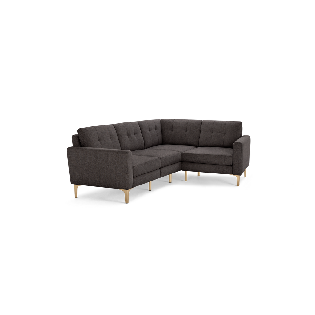 Dark gray fabric L-shaped sectional sofa with tufted back cushions and light wood legs on black background.