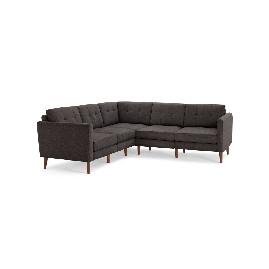 Dark gray L-shaped sectional sofa with tufted cushions and wooden legs, showcasing a modern mid-century design.