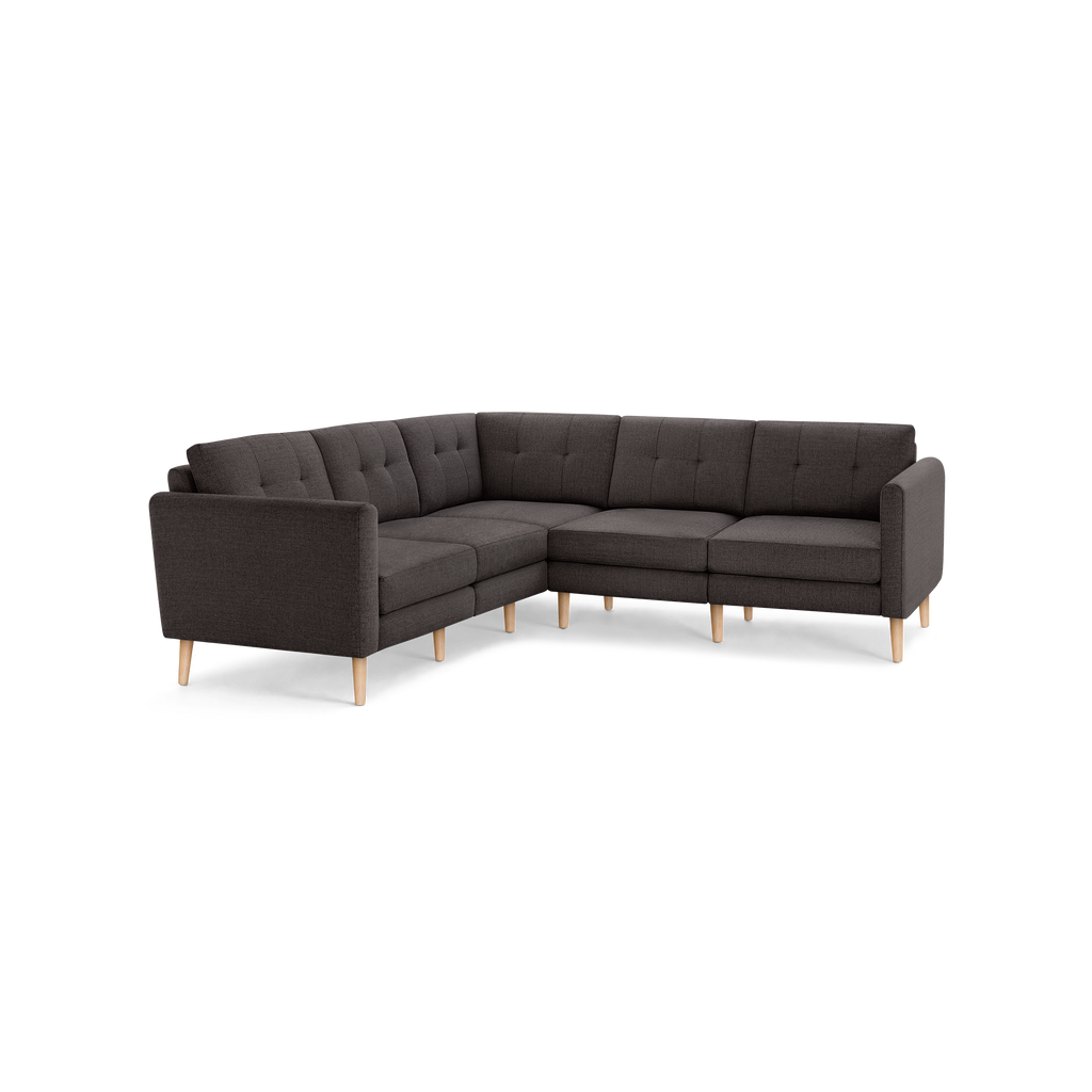 Dark gray fabric L-shaped sectional sofa with button-tufted backrest cushions and light wooden tapered legs.