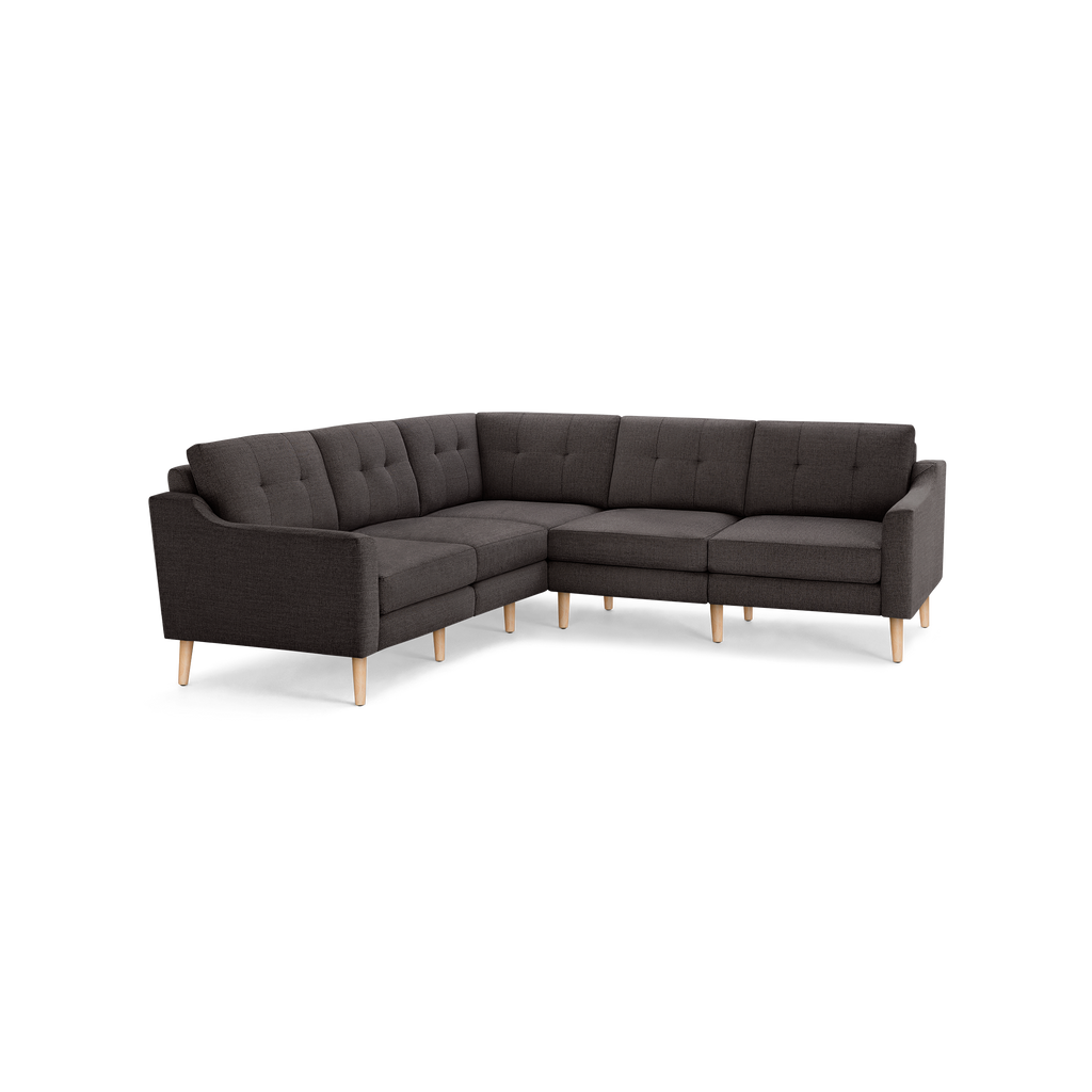 L-shaped dark gray fabric sectional sofa with tufted back cushions and light wooden tapered legs.