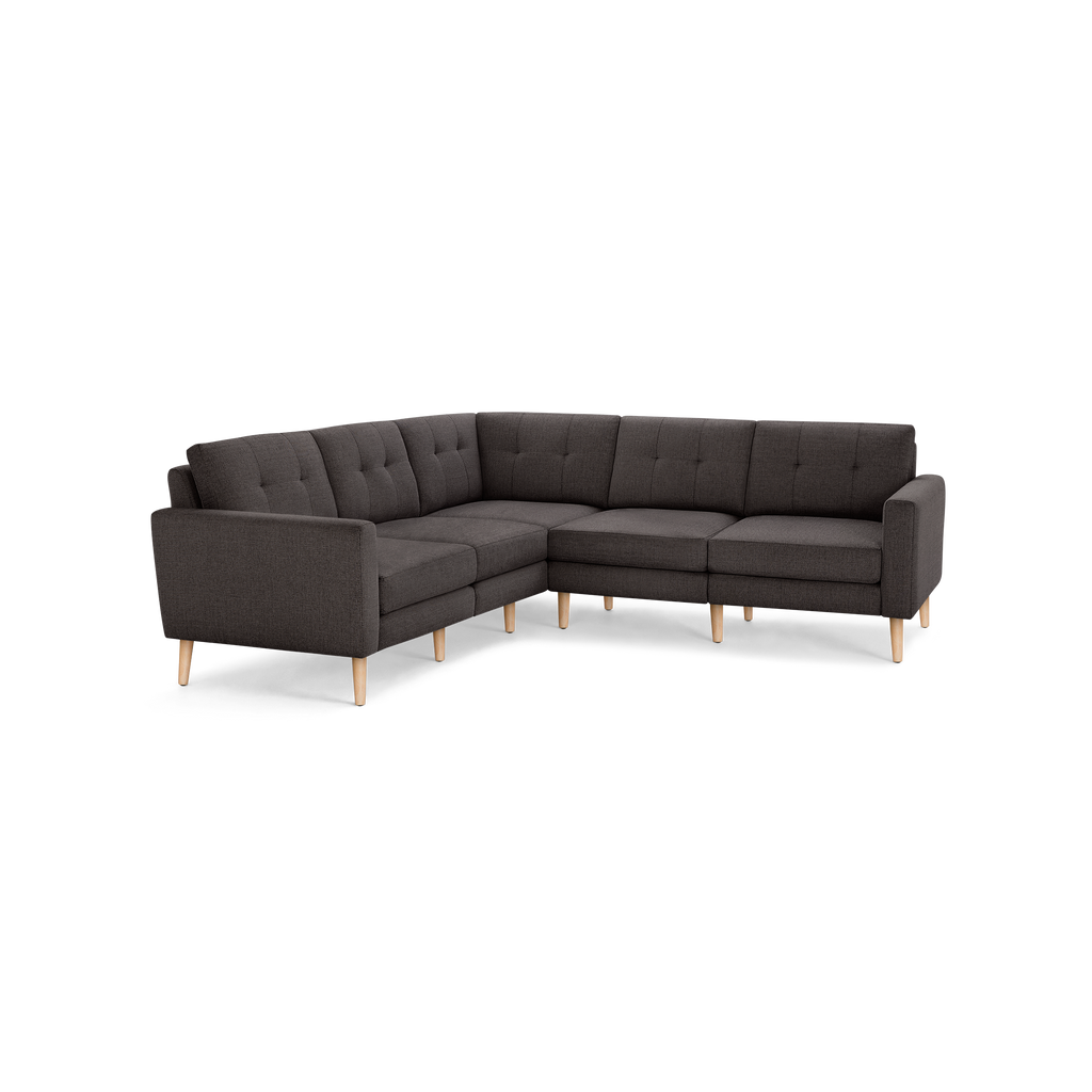 Dark gray fabric L-shaped sectional sofa with tufted back cushions and light wooden legs, modern minimalist design.
