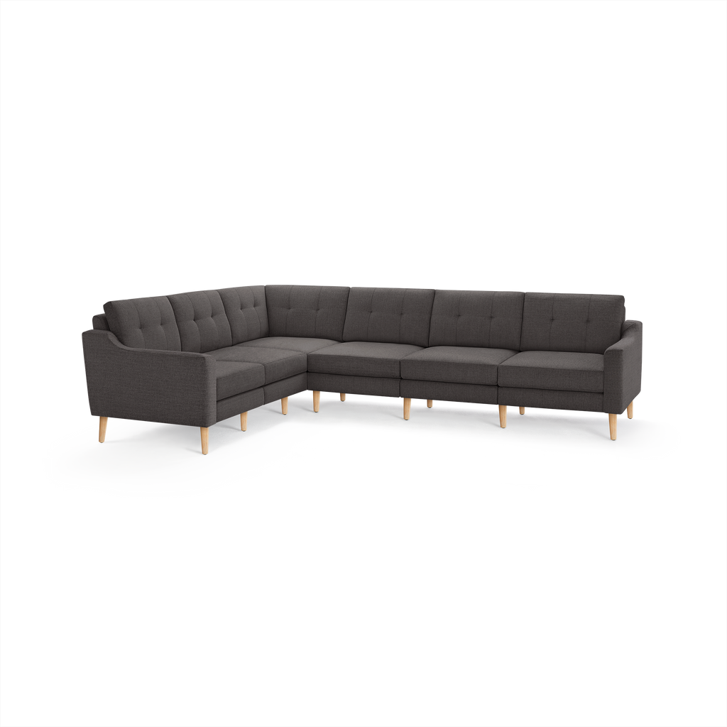 Dark gray upholstered L-shaped sectional sofa with tufted back cushions and light wooden tapered legs.