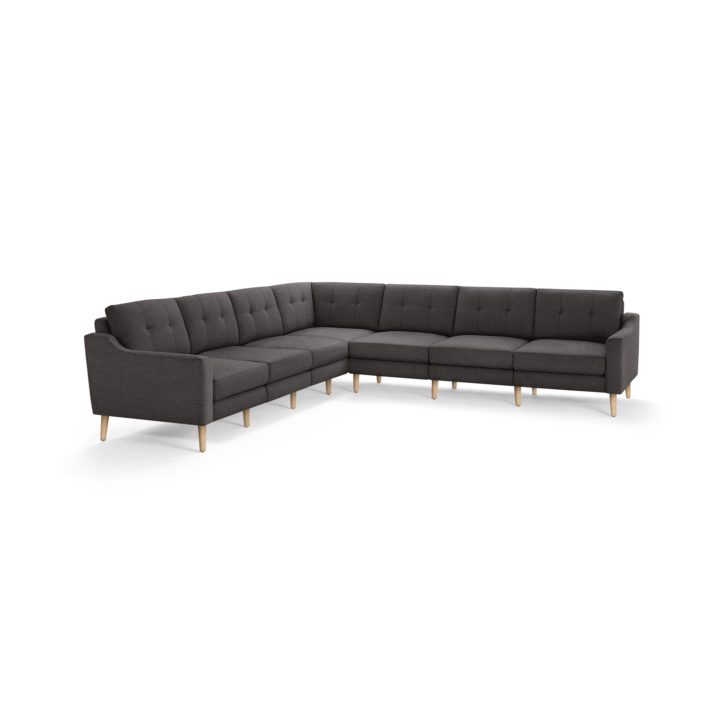 Large L-shaped sectional sofa in dark gray fabric with tufted back cushions and light wooden legs.