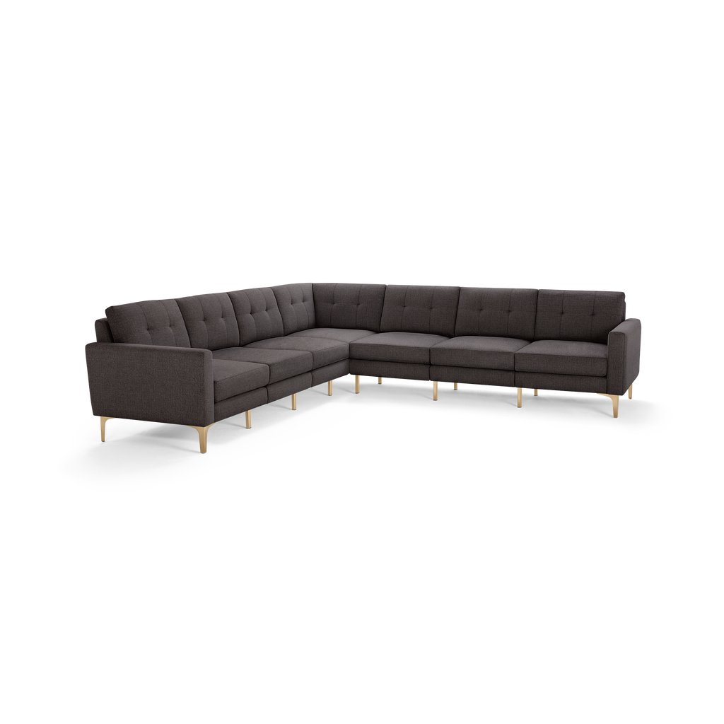 Large modern L-shaped sectional sofa in dark grey fabric with tufted back cushions and light wooden legs.