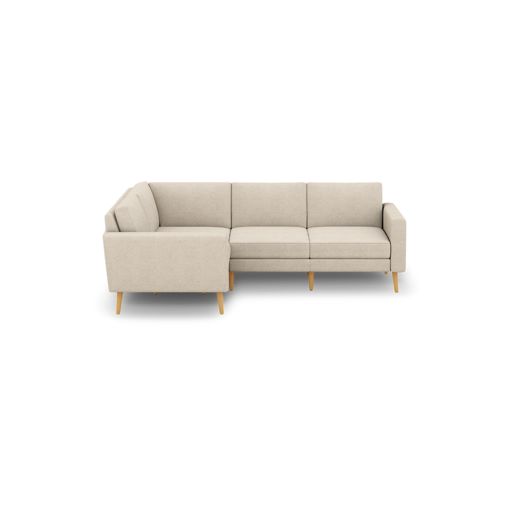 Beige fabric L-shaped sectional sofa with cushioned seats and backs, supported by light wooden legs, isolated on black background.