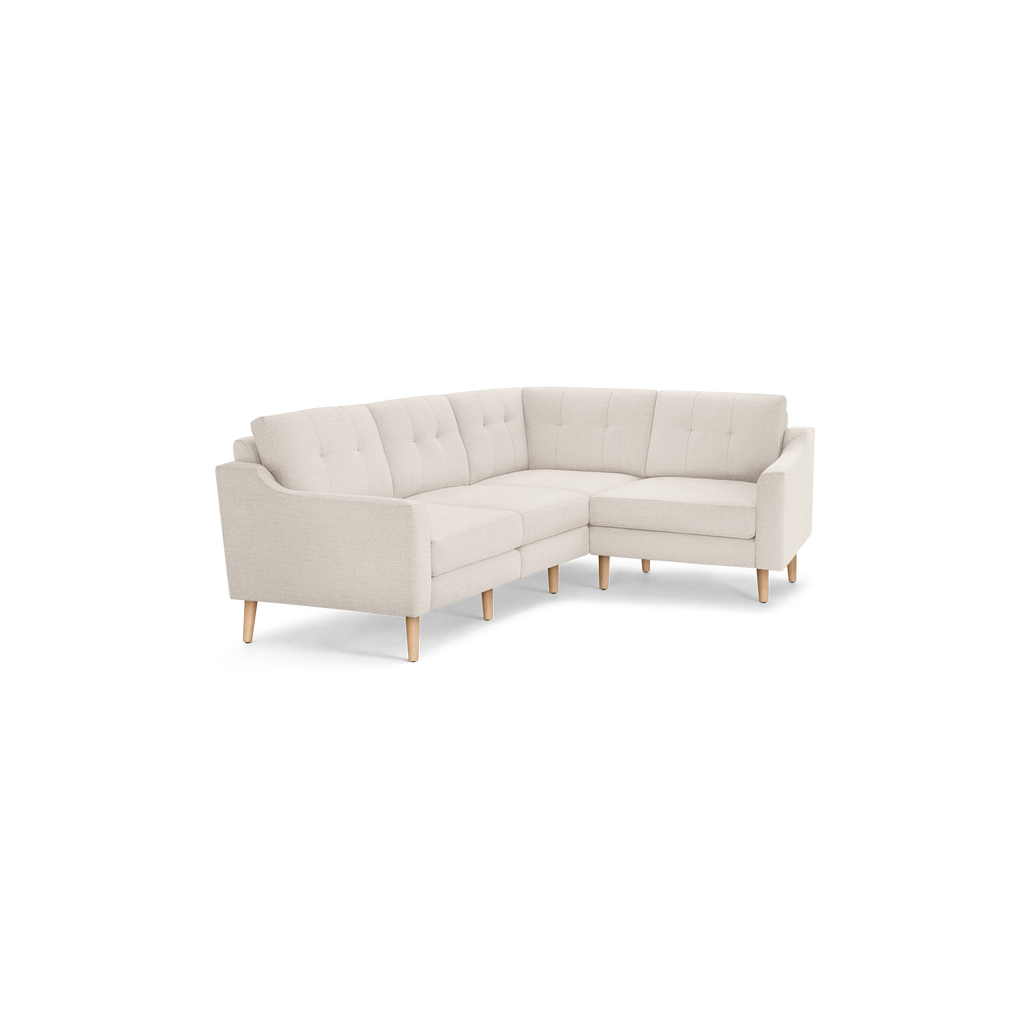 Beige L-shaped sectional sofa with tufted back cushions, slim armrests, and light wooden legs, minimalist modern design.