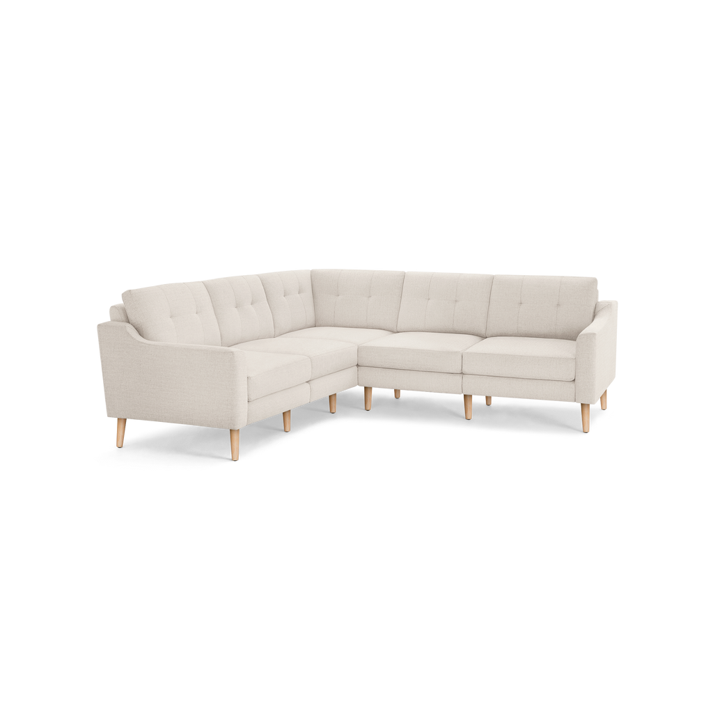 Beige fabric sectional sofa with tufted back cushions and angled wooden legs, designed in a modern mid-century style.
