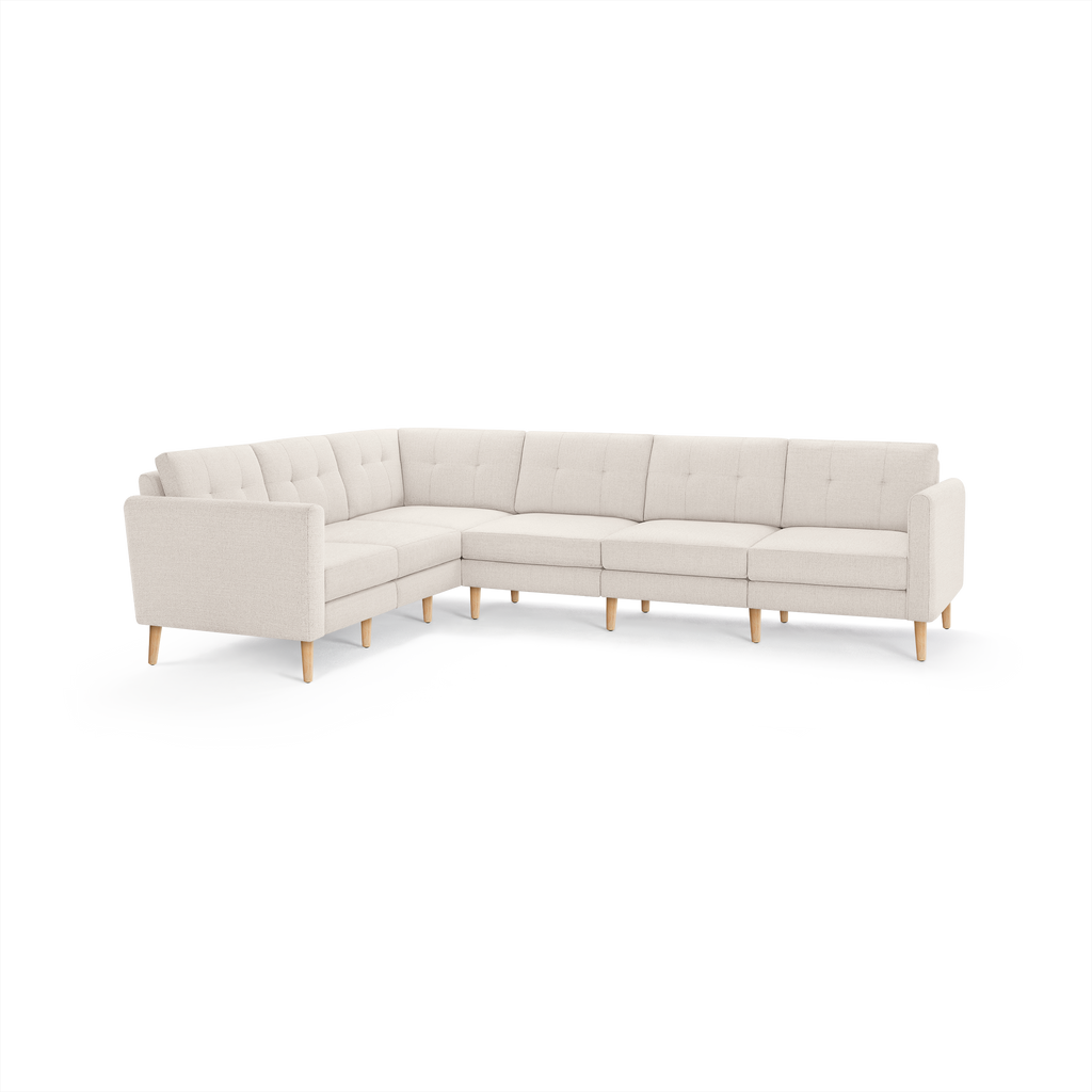 L-shaped beige sectional sofa with tufted cushions, wooden legs, and clean modern design, suitable for spacious living rooms.