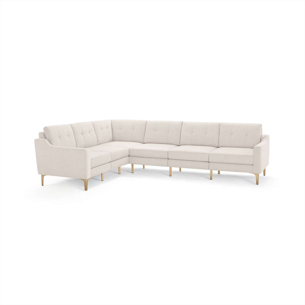 Modern L-shaped sectional sofa with cream-colored tufted fabric upholstery and light wooden legs.