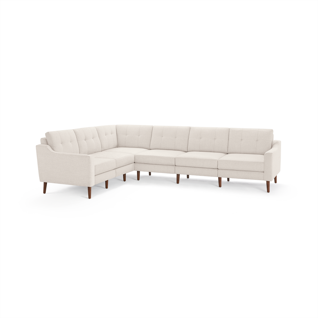 Light beige L-shaped sectional sofa with tufted back cushions and wooden legs, showcasing mid-century modern design.