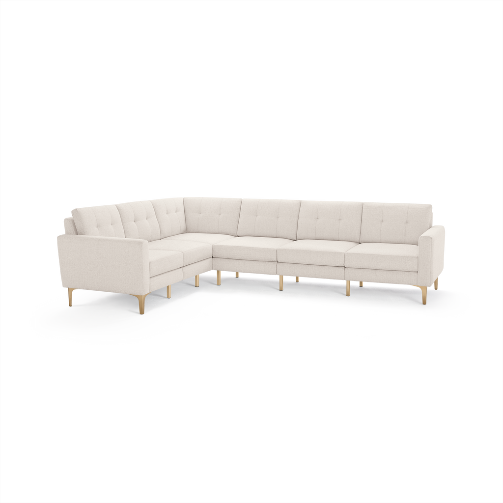 Light beige L-shaped sectional sofa with tufted back cushions, slim armrests, and wooden legs.