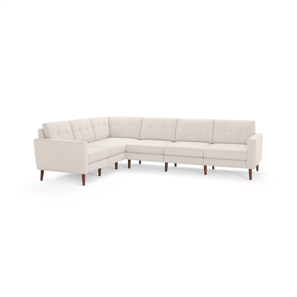 Cream-colored L-shaped sectional sofa with tufted back cushions and wooden legs on a white background.