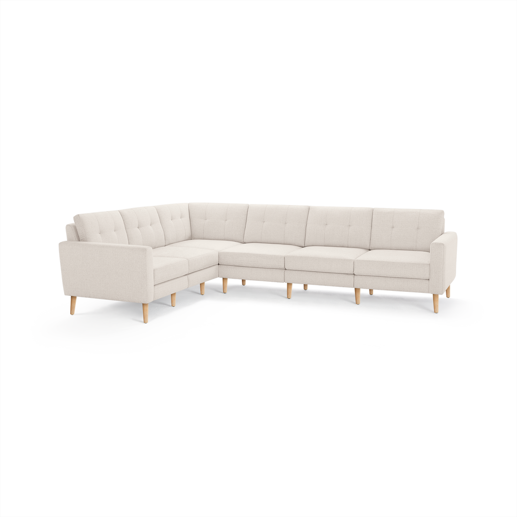Light beige L-shaped sectional sofa with tufted back cushions and wooden tapered legs, featuring clean modern design.