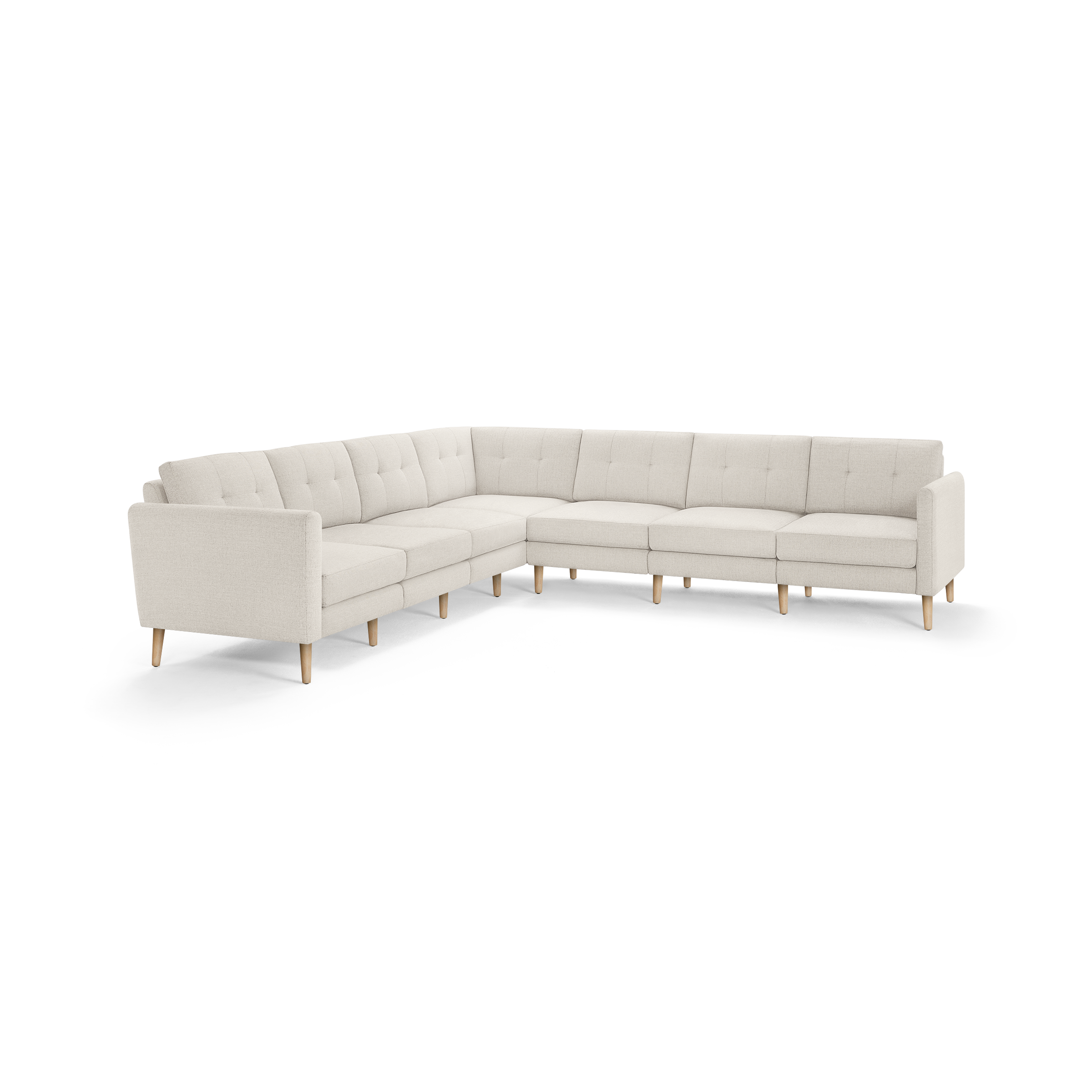 Large L-shaped beige fabric sectional sofa with tufted back cushions and light wooden legs on white background.