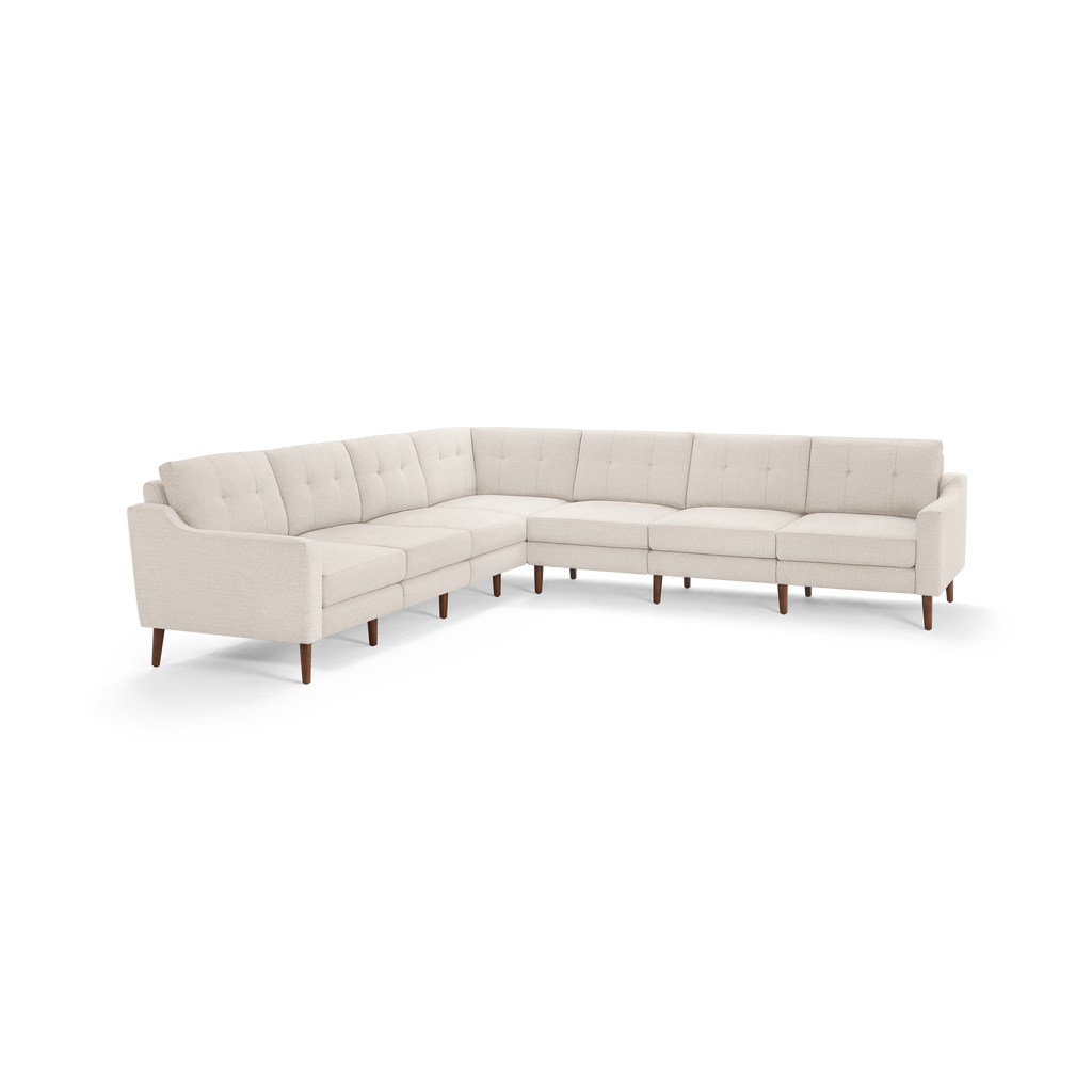 Large beige L-shaped sectional sofa with tufted cushions, angled armrests, and wooden legs on a white background.