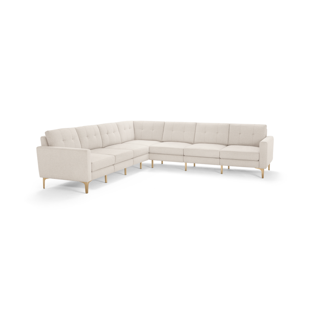 Large modern L-shaped sectional sofa with light beige tufted fabric upholstery and slim wooden legs.