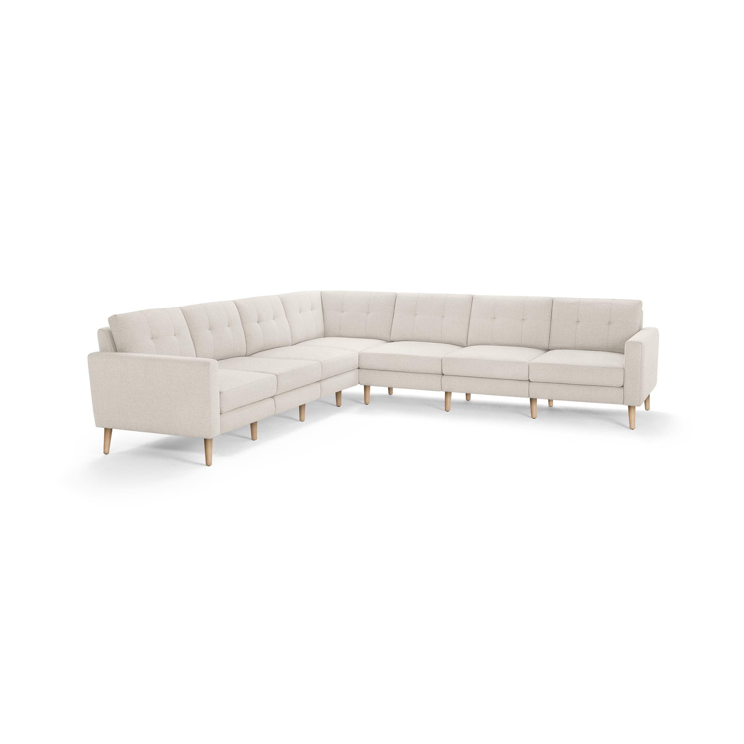 Large L-shaped sectional sofa with beige tufted fabric upholstery, clean lines, and light wooden tapered legs.