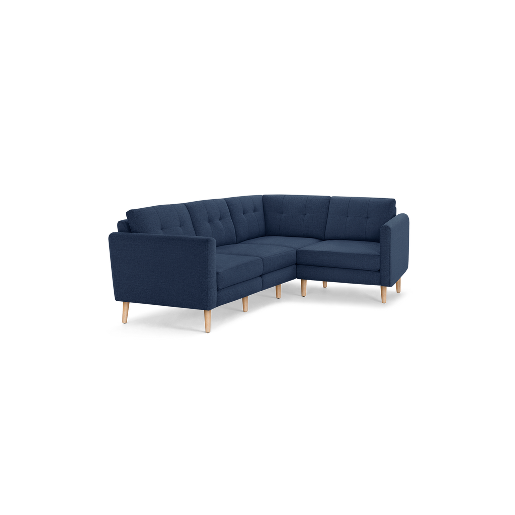 Modern L-shaped navy blue fabric sectional sofa with tufted cushions and light wooden legs, designed for corner seating.