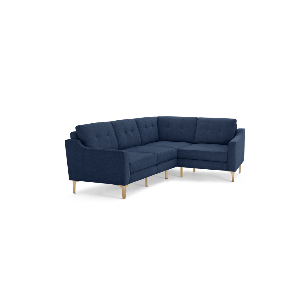 Modern navy blue fabric sectional sofa with tufted back cushions and light wooden legs on black background.
