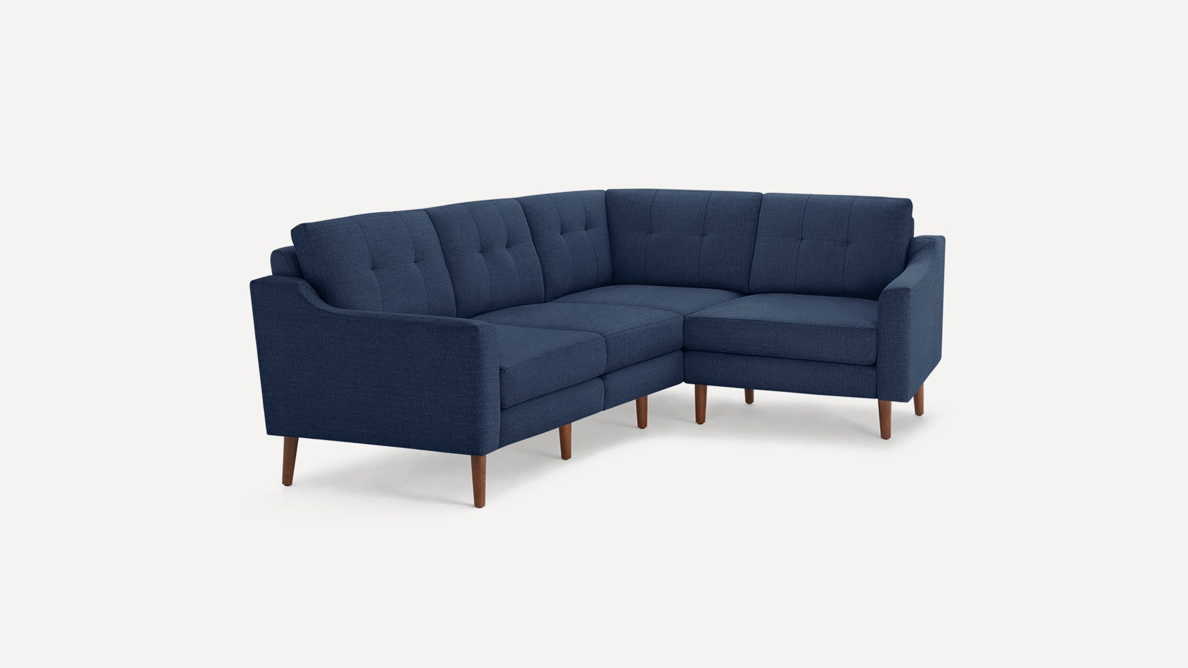 Modern navy blue L-shaped sectional sofa with tufted cushions and wooden tapered legs on a plain white background.
