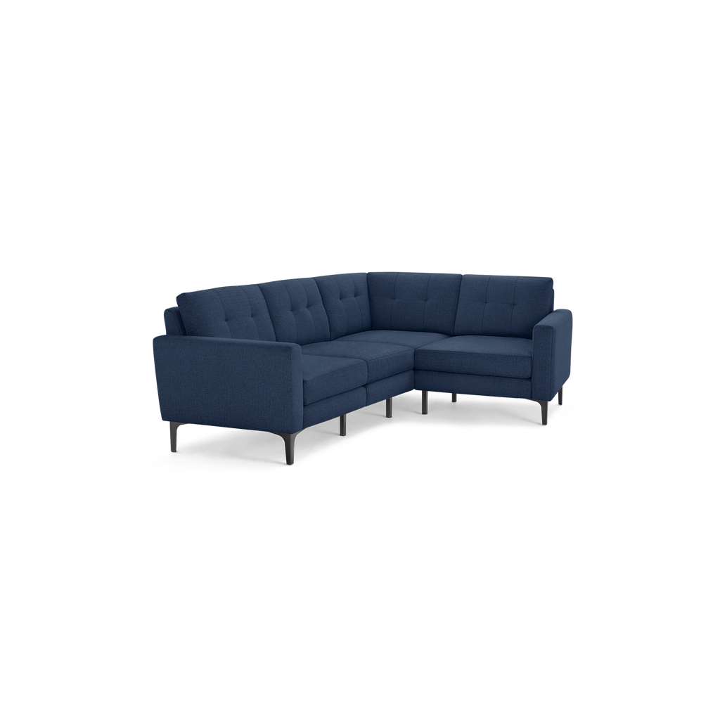 Modern L-shaped sectional sofa in dark blue fabric with tufted back cushions and sleek black legs.