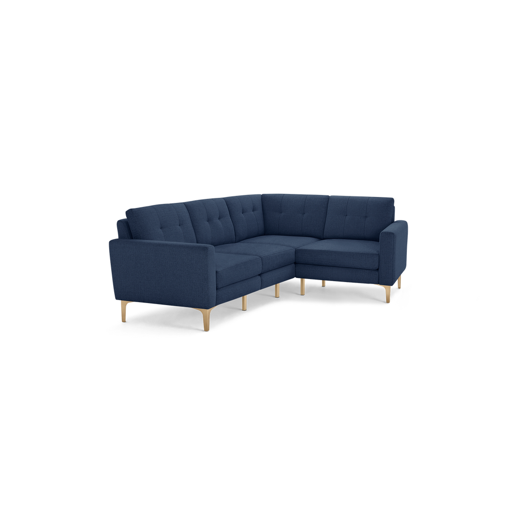Modern navy blue fabric sectional sofa with tufted cushions and light wooden legs, angled for corner placement.