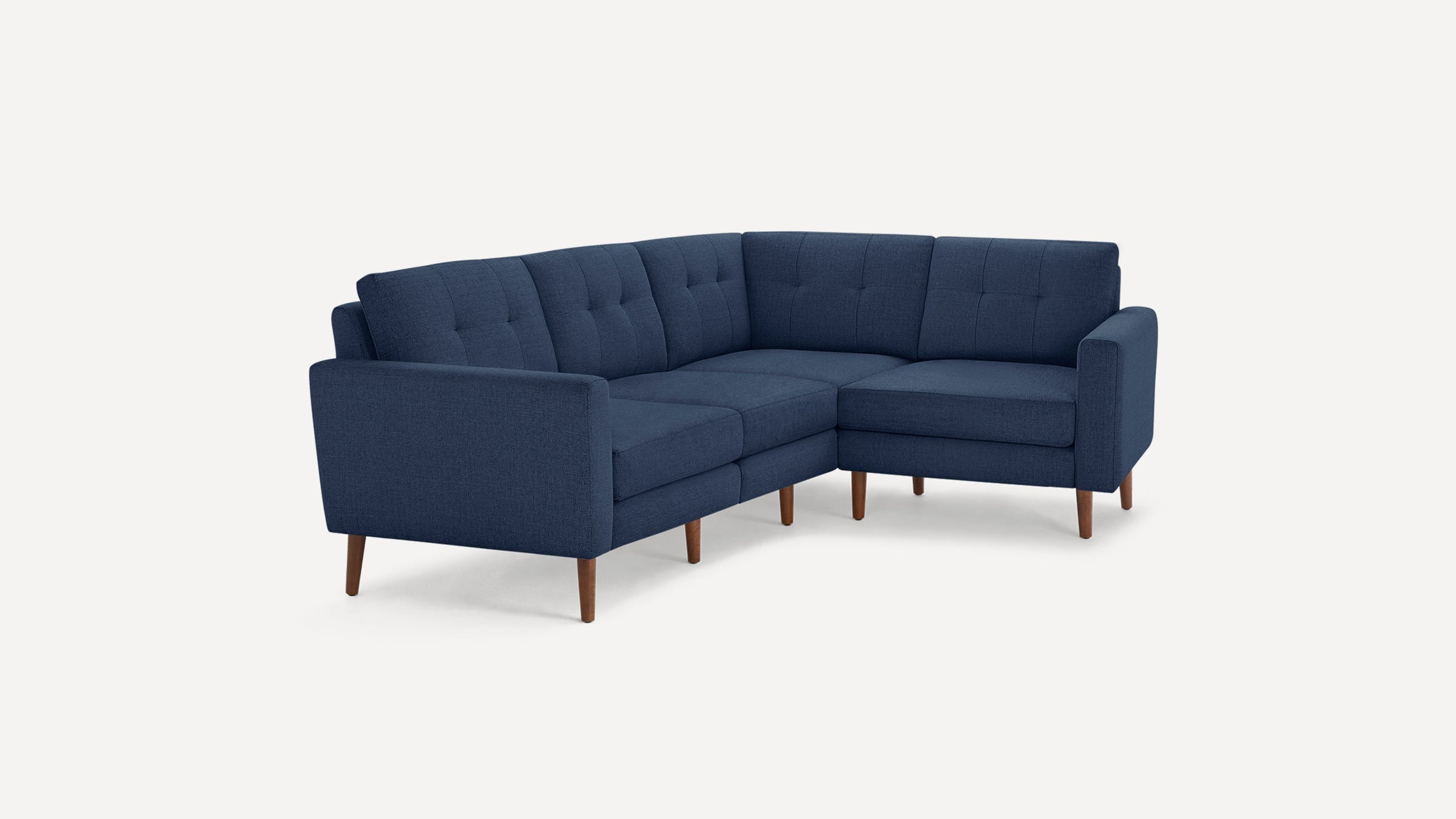 Modern navy blue fabric sectional sofa with tufted cushions, straight arms, and wooden tapered legs on a white background.