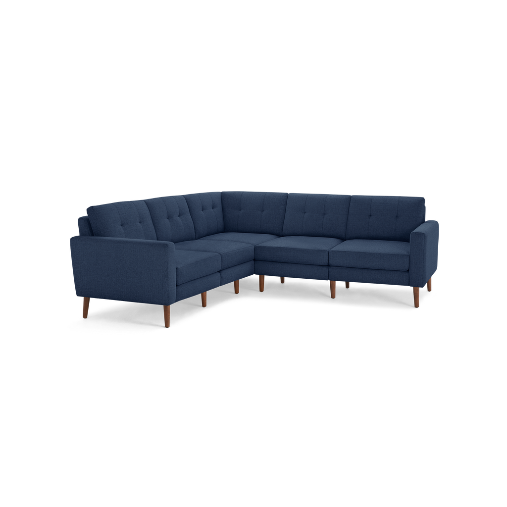Modern L-shaped sectional sofa upholstered in dark blue fabric, featuring tufted cushions and wooden legs.