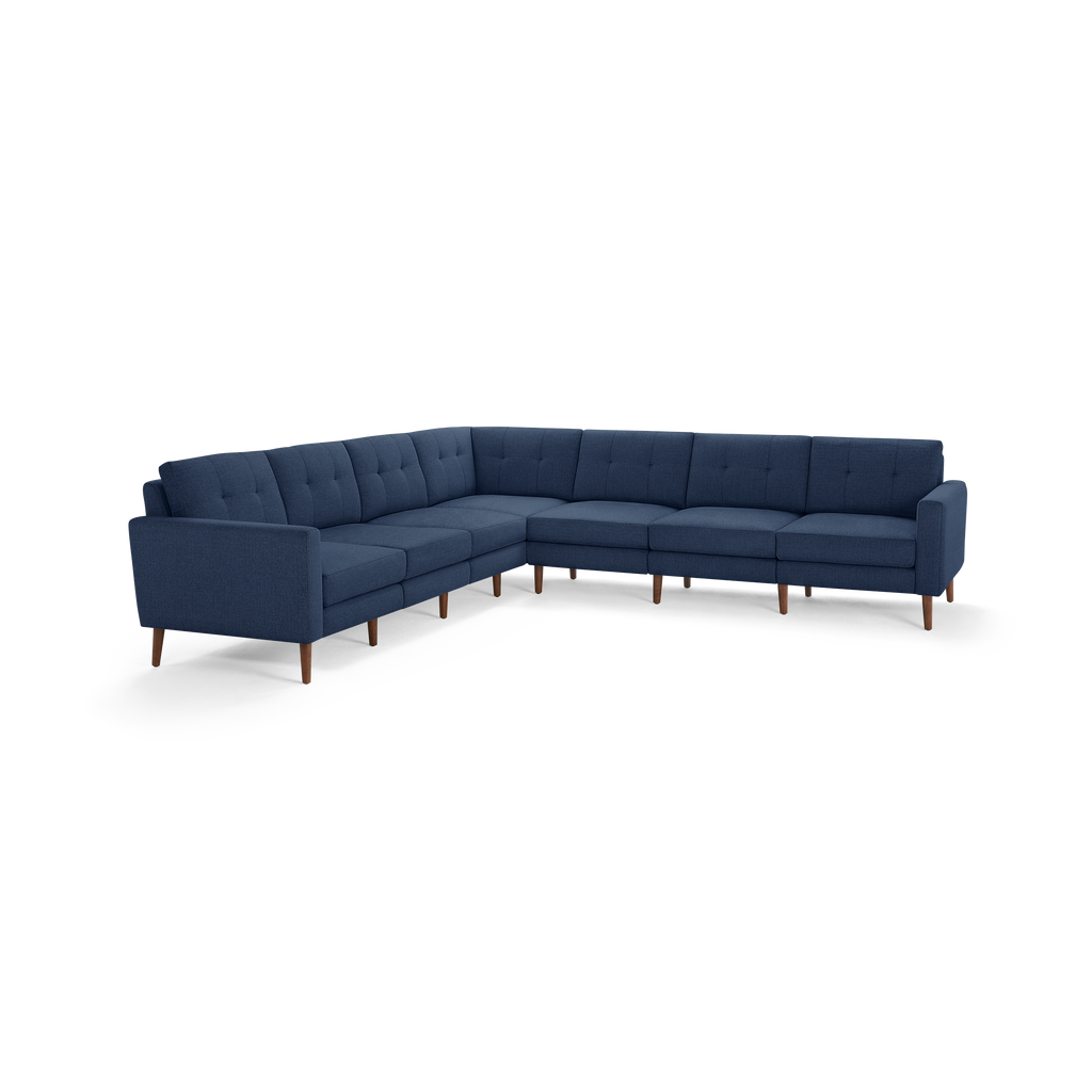 Large L-shaped sectional sofa with deep blue fabric upholstery, tufted back cushions, and wooden tapered legs.