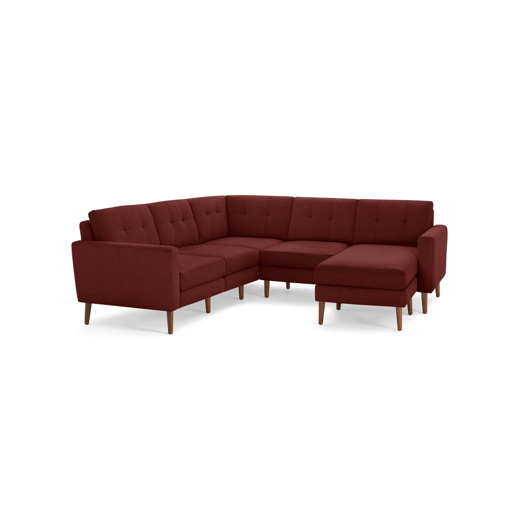 Modern L-shaped sectional sofa in deep red fabric with tufted back cushions and wooden legs, featuring a chaise lounge on the right side.