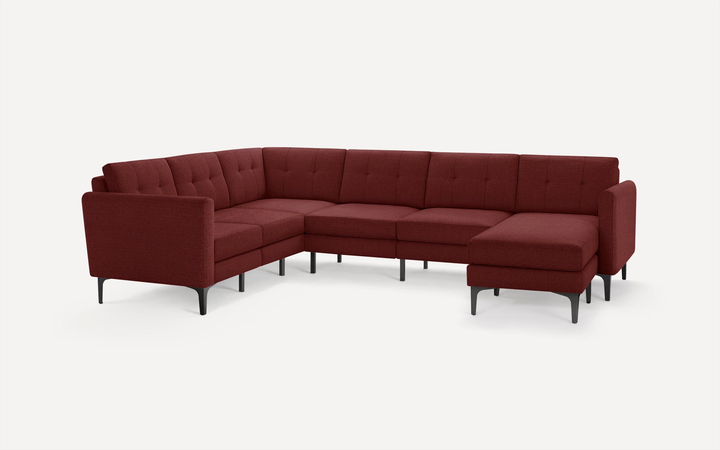 Modern L-shaped sectional sofa in deep burgundy fabric with tufted back cushions and black tapered legs, designed for spacious seating.