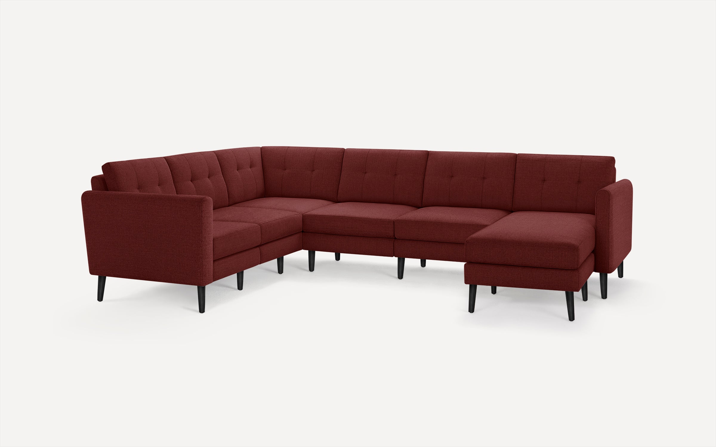Modern sectional sofa in deep red fabric with tufted cushions, straight armrests, and black tapered legs on white background.