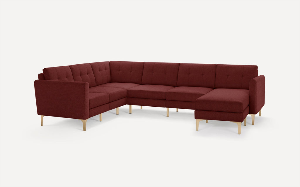 Modern L-shaped sectional sofa in deep burgundy fabric with tufted back cushions and light wooden angled legs on white background.