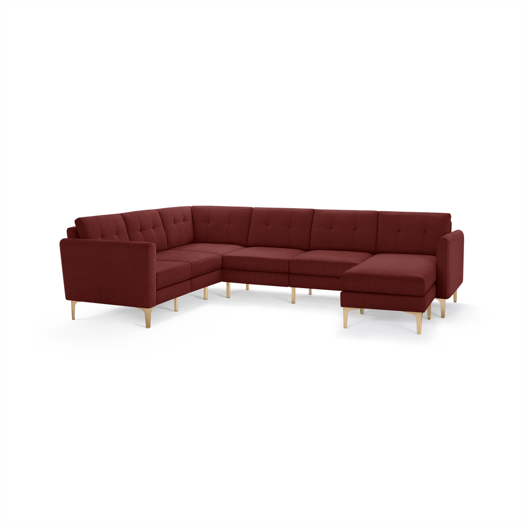 Modern L-shaped sectional sofa in deep burgundy fabric with tufted back cushions and light wooden legs.