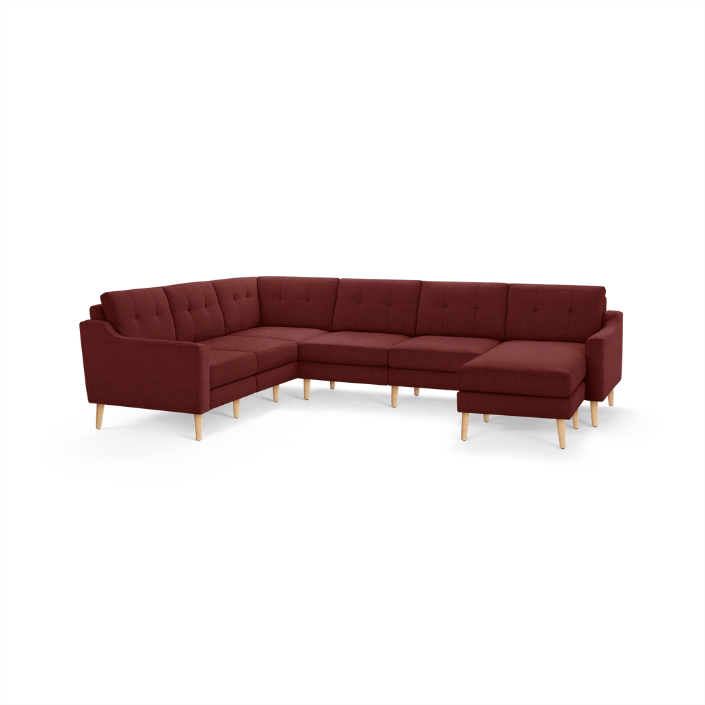 Large L-shaped sectional sofa in deep red fabric with tufted back cushions and light wooden legs.