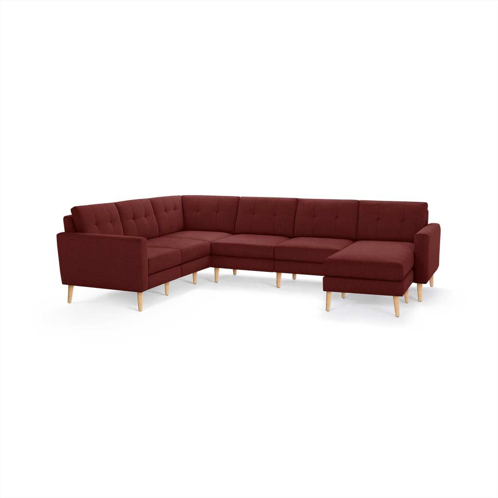 Large L-shaped sectional sofa with deep red fabric upholstery, tufted back cushions, and light wood tapered legs.